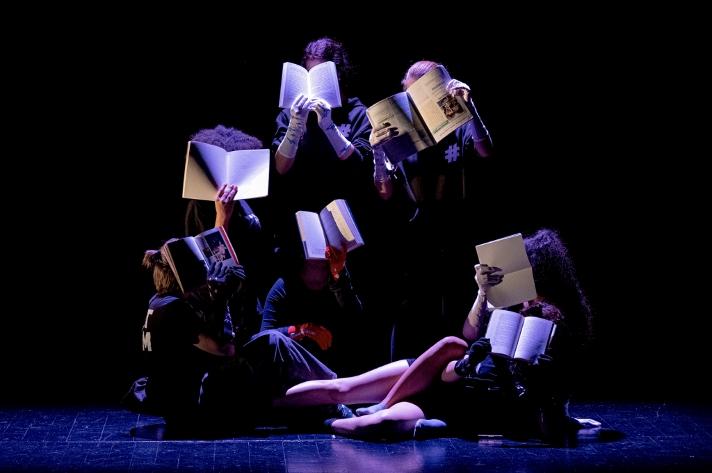 Students during the theatre performance placing books in front of their faces.